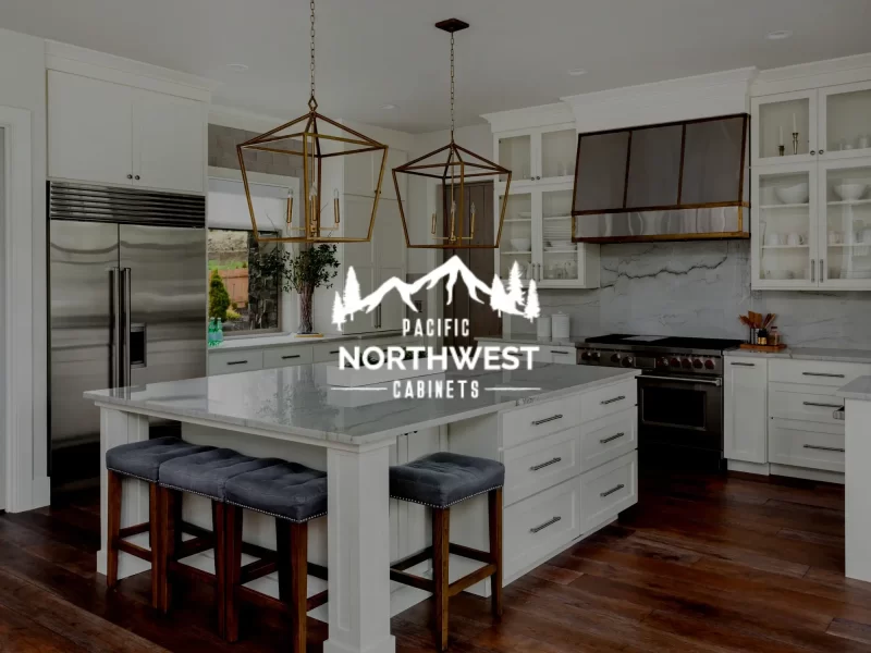 An image of a modern kitchen with white cabinets and white granite countertops. The Pacific Northwest Cabinets logo is superimposed on the front.