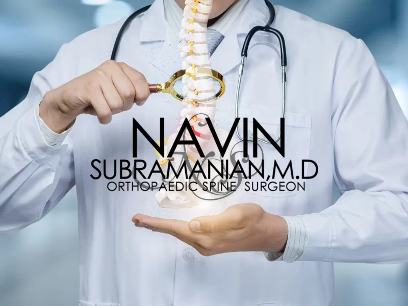 An image of a doctor holding a magnifying glass and looking at a human spine. The logo for Dr. Navin Subramanian is superimposed on the front of the image.