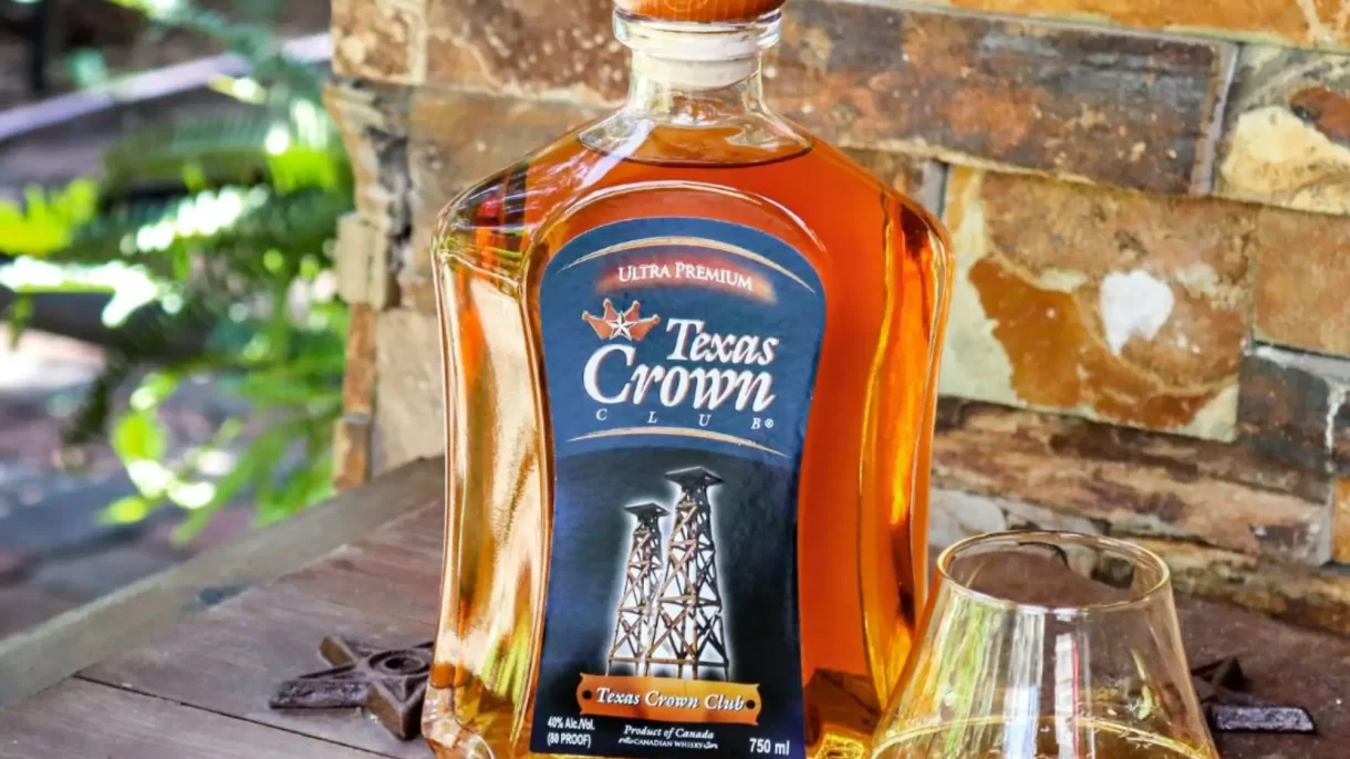 An image of Texas Crown Club Whisky sitting on a table outside with a glass poured.