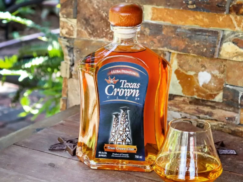 An image of Texas Crown Club Whisky sitting on a table outside with a glass poured.